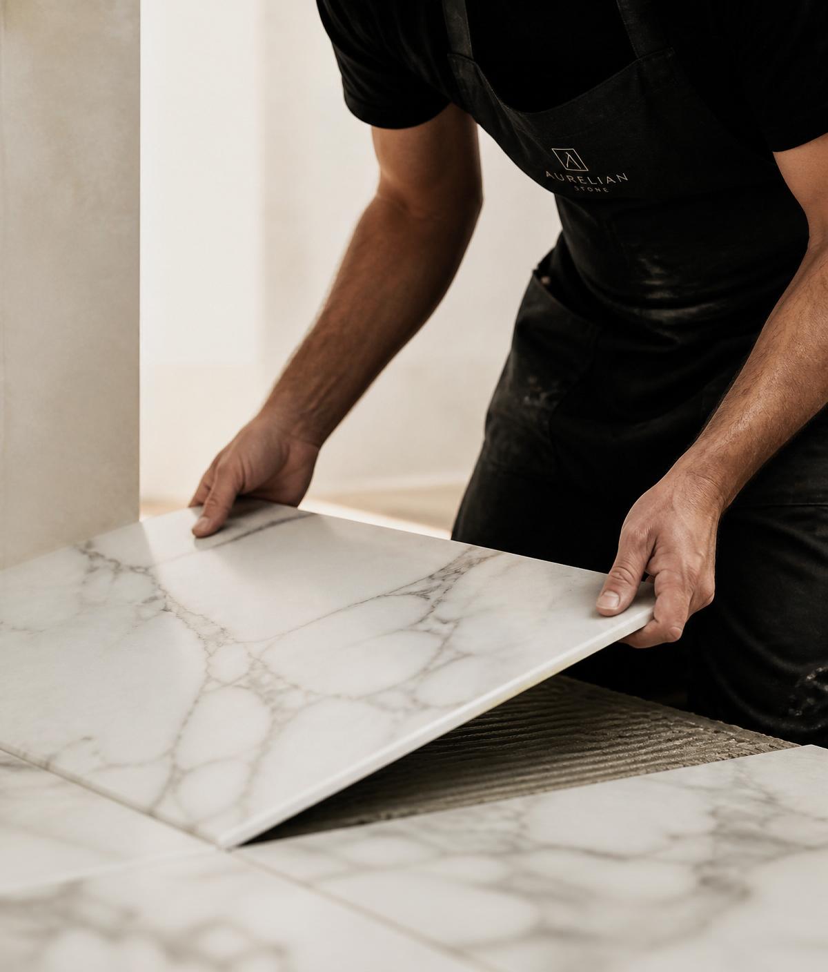 Master tile installer placing a marble slab by hand